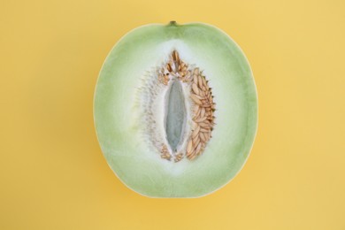 Half of fresh ripe honeydew melon on yellow background, top view