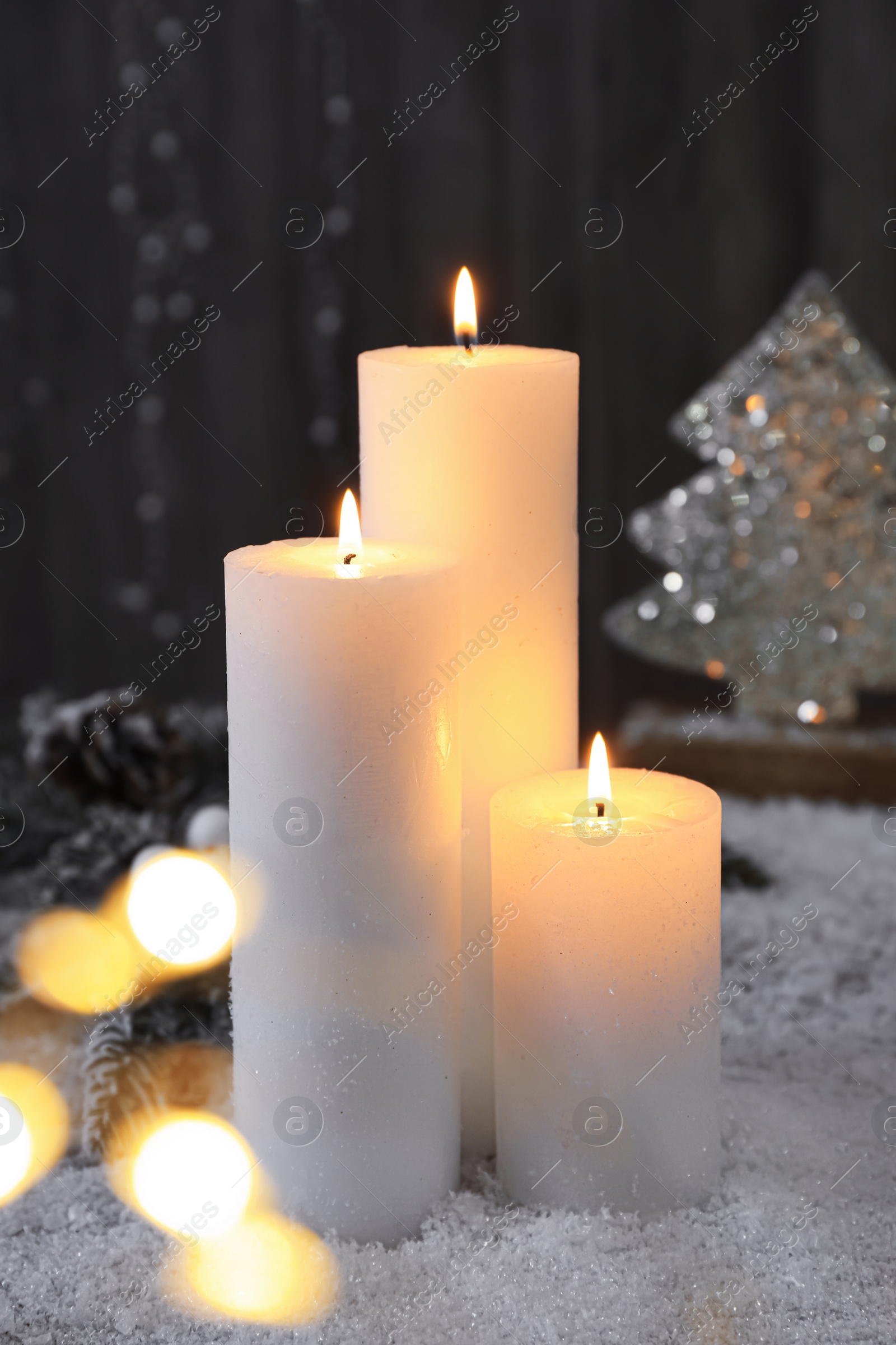 Photo of Burning candles and Christmas decor on artificial snow