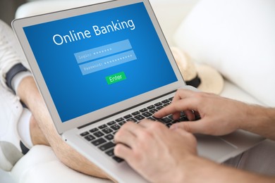 Image of Man using online banking application on laptop indoors, closeup