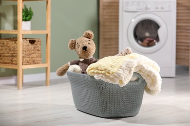 Photo of Laundry basket with soft blankets and toy in bathroom