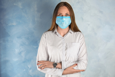 Woman with disposable mask on face against light blue background