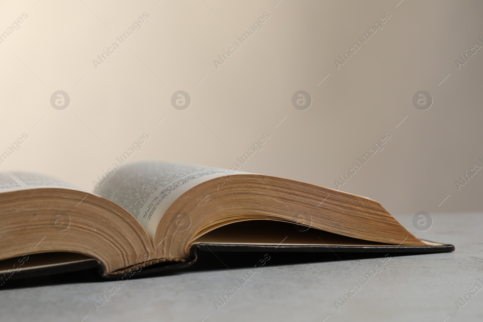 Photo of Open hardcover Bible on light grey table, closeup with space for text. Religious book