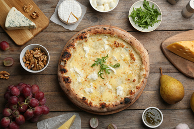 Photo of Delicious cheese pizza and fresh ingredients on wooden table, flat lay