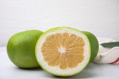 Photo of Whole and cut sweetie fruits on white table, closeup