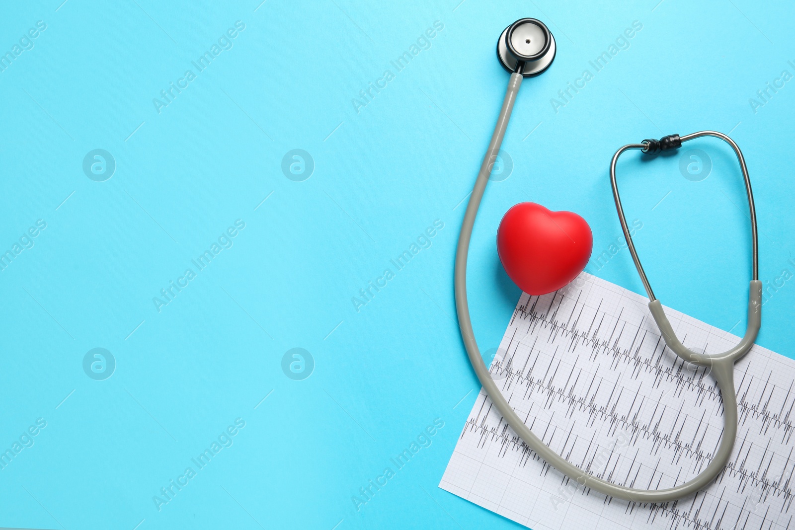 Photo of Stethoscope, cardiogram and red decorative heart on light blue background, flat lay with space for text. Cardiology concept