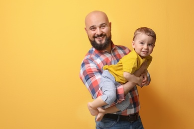 Portrait of dad and his little son on color background