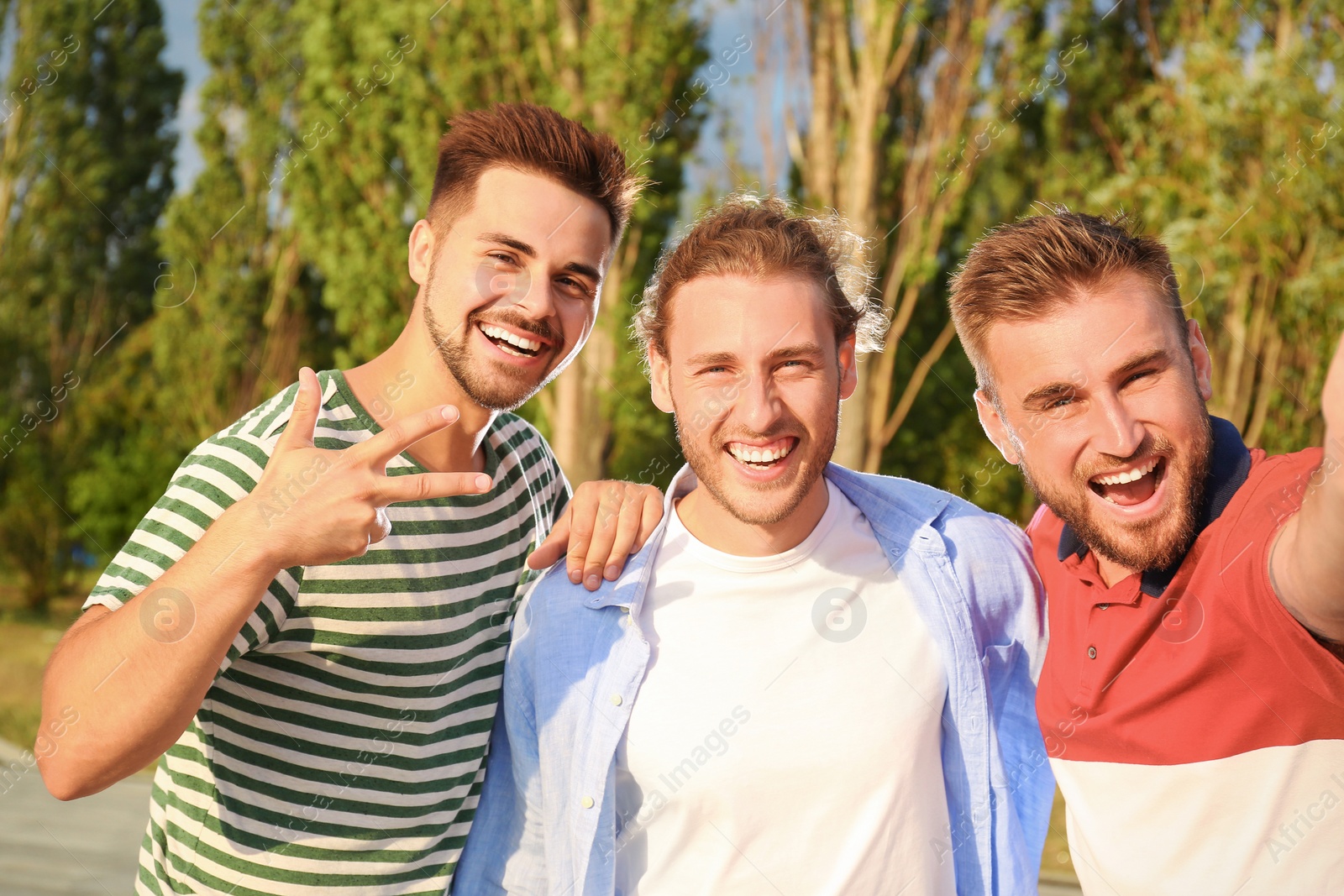 Photo of Happy young men taking selfie outdoors on sunny day