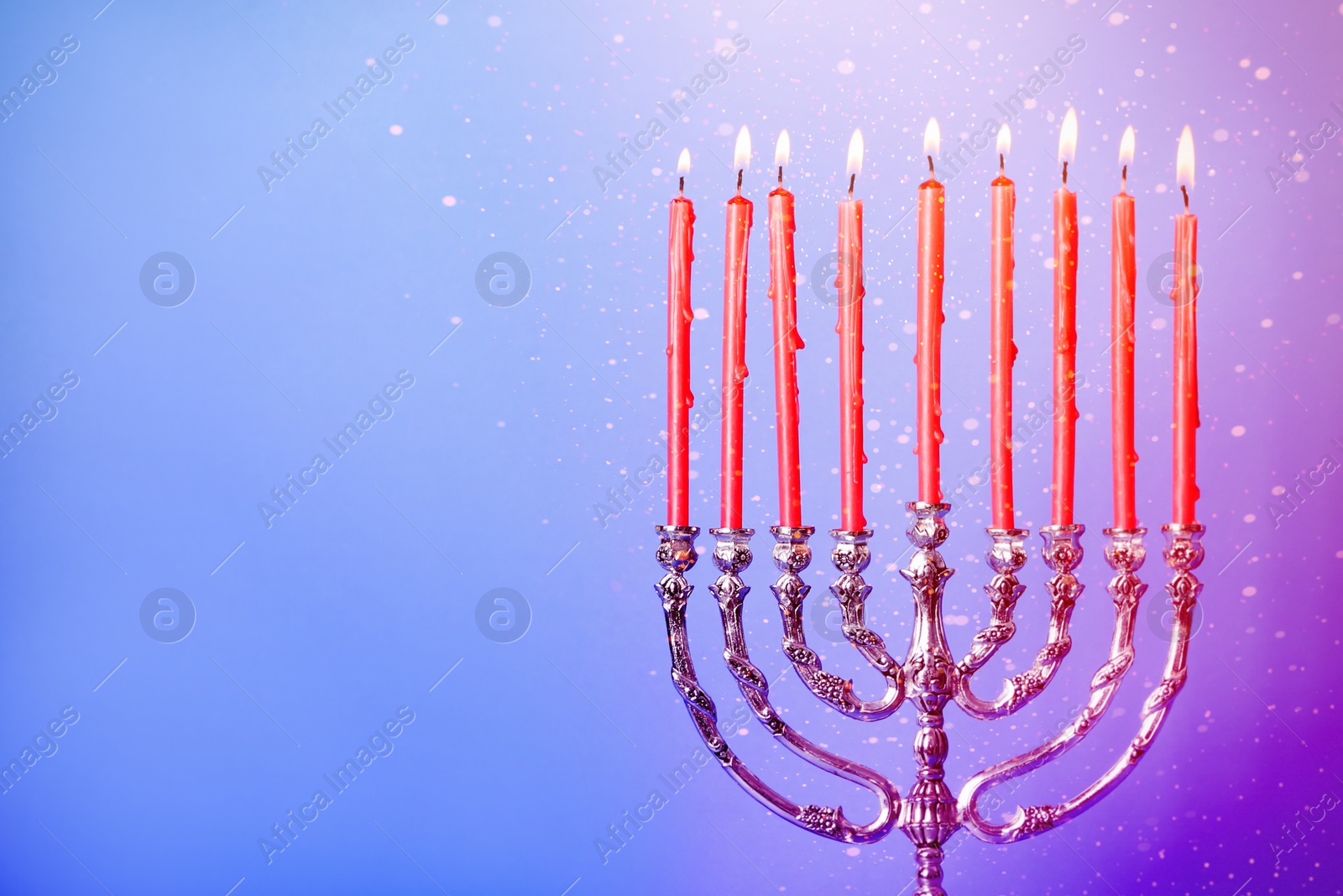 Image of Silver menorah with burning candles on color background, space for text. Hanukkah celebration