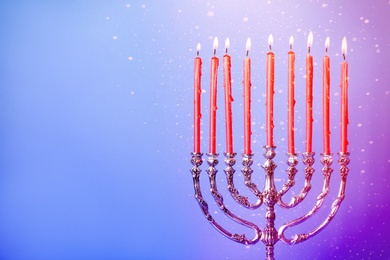 Silver menorah with burning candles on color background, space for text. Hanukkah celebration