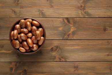 Photo of Bowl of jackfruit seeds on wooden table, top view. Space for text