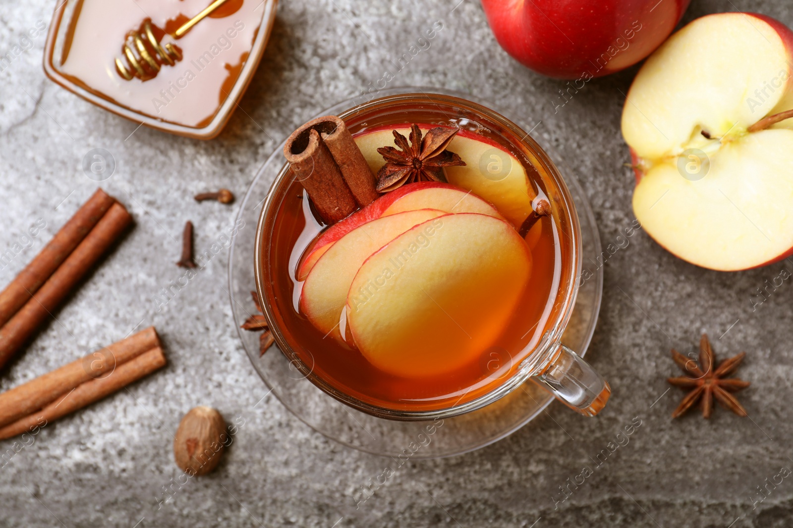 Photo of Aromatic hot mulled cider on grey table, flat lay