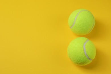 Two tennis balls on yellow background, above view. Space for text