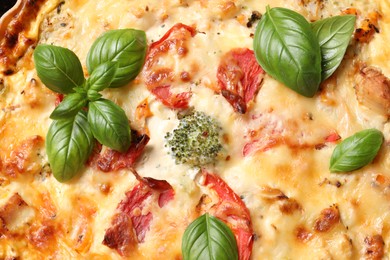 Photo of Tasty quiche with tomatoes, basil and cheese as background, closeup