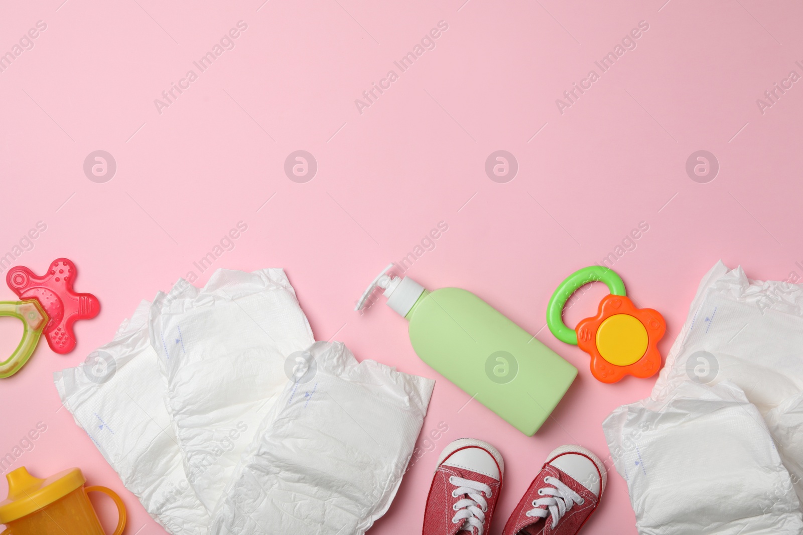 Photo of Diapers and baby accessories on pink background, flat lay. Space for text