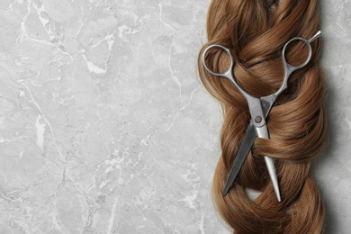 Photo of Flat lay composition with brown hair, scissors and space for text on grey background. Hairdresser service