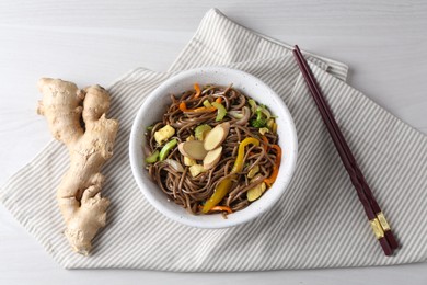 Photo of Stir-fry. Delicious cooked noodles with chicken and vegetables in bowl served on light wooden table, flat lay