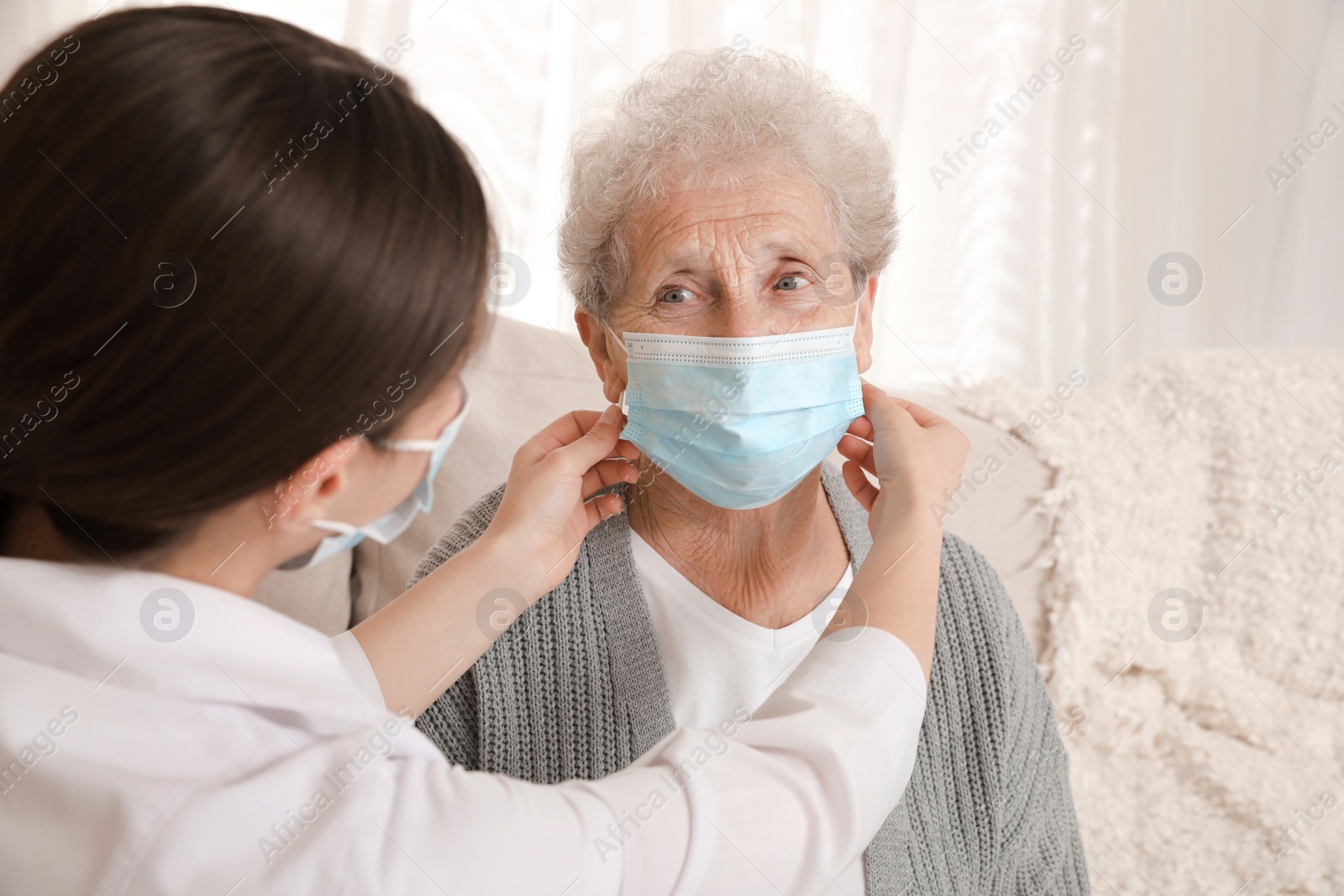 Photo of Doctor putting protective mask on senior woman at nursing home