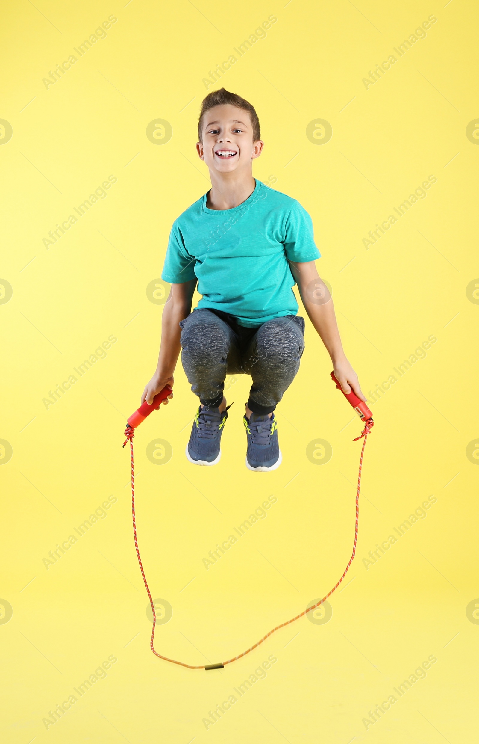 Photo of Full length portrait of boy jumping rope on color background