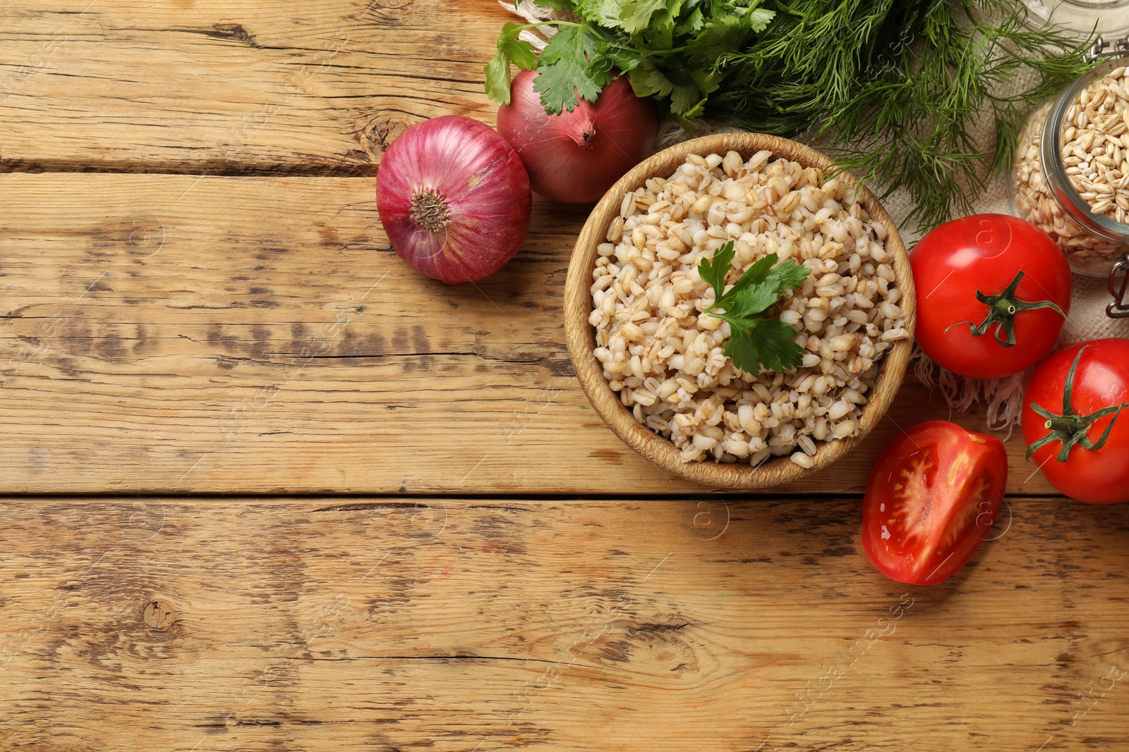 Photo of Delicious pearl barley in bowl served on wooden table, flat lay. Space for text