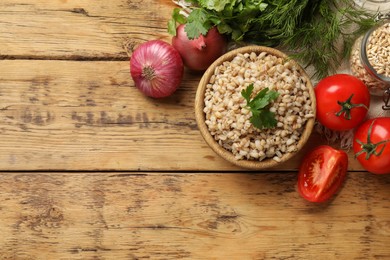 Photo of Delicious pearl barley in bowl served on wooden table, flat lay. Space for text