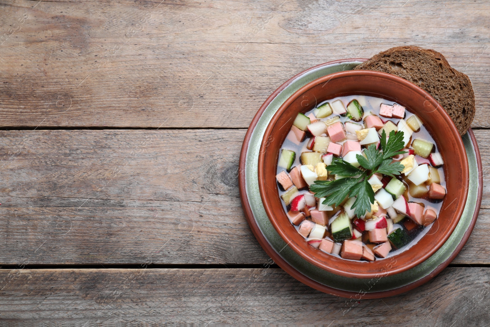 Photo of Delicious cold okroshka with kvass and space for text on wooden table, top view. Traditional Russian summer soup