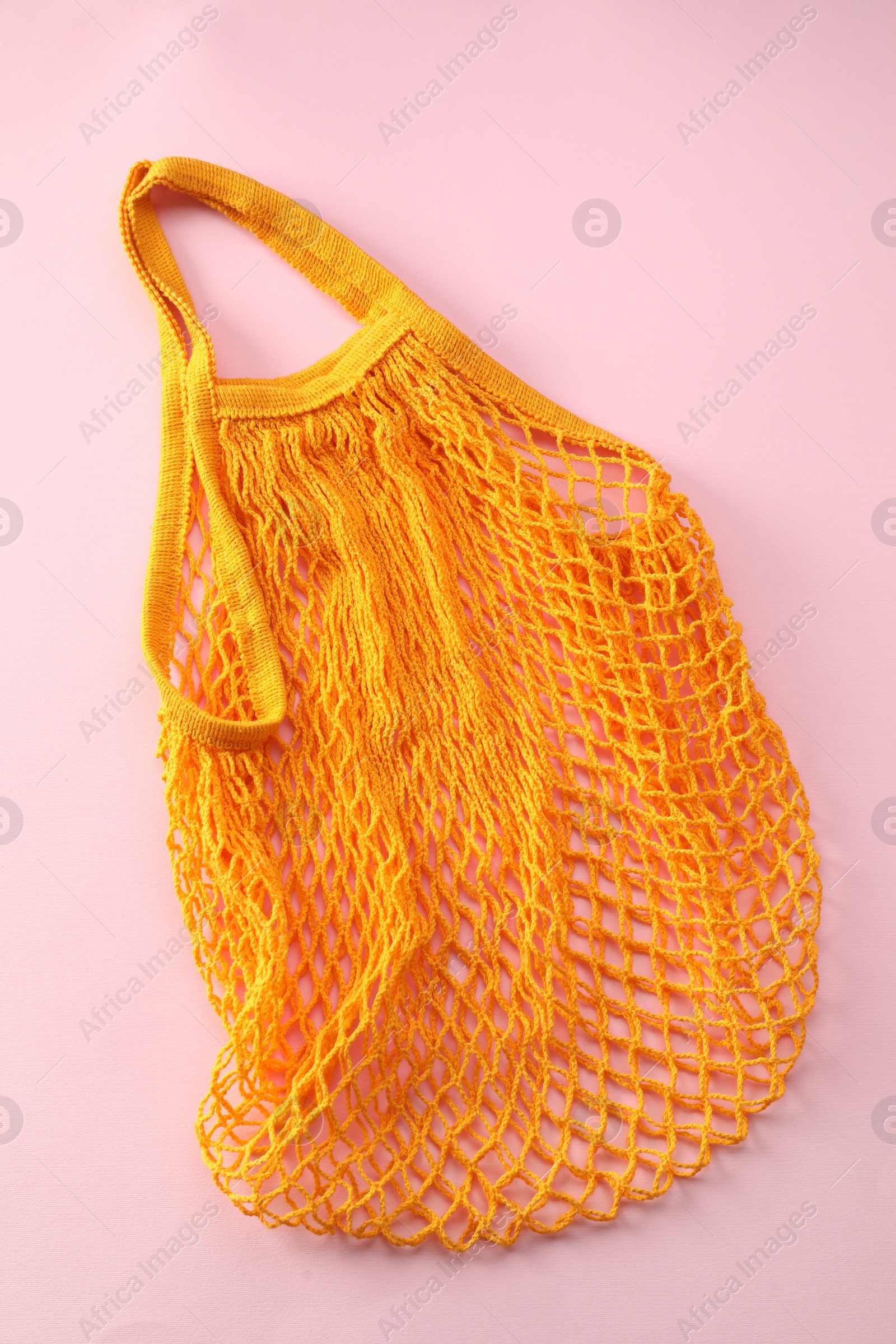 Photo of Orange string bag on pink background, top view