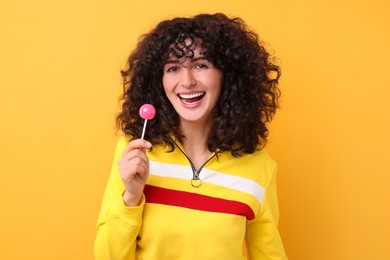 Beautiful woman with lollipop on yellow background