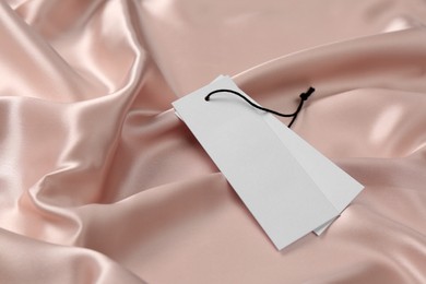 Blank white tags on pink silky fabric. Space for text