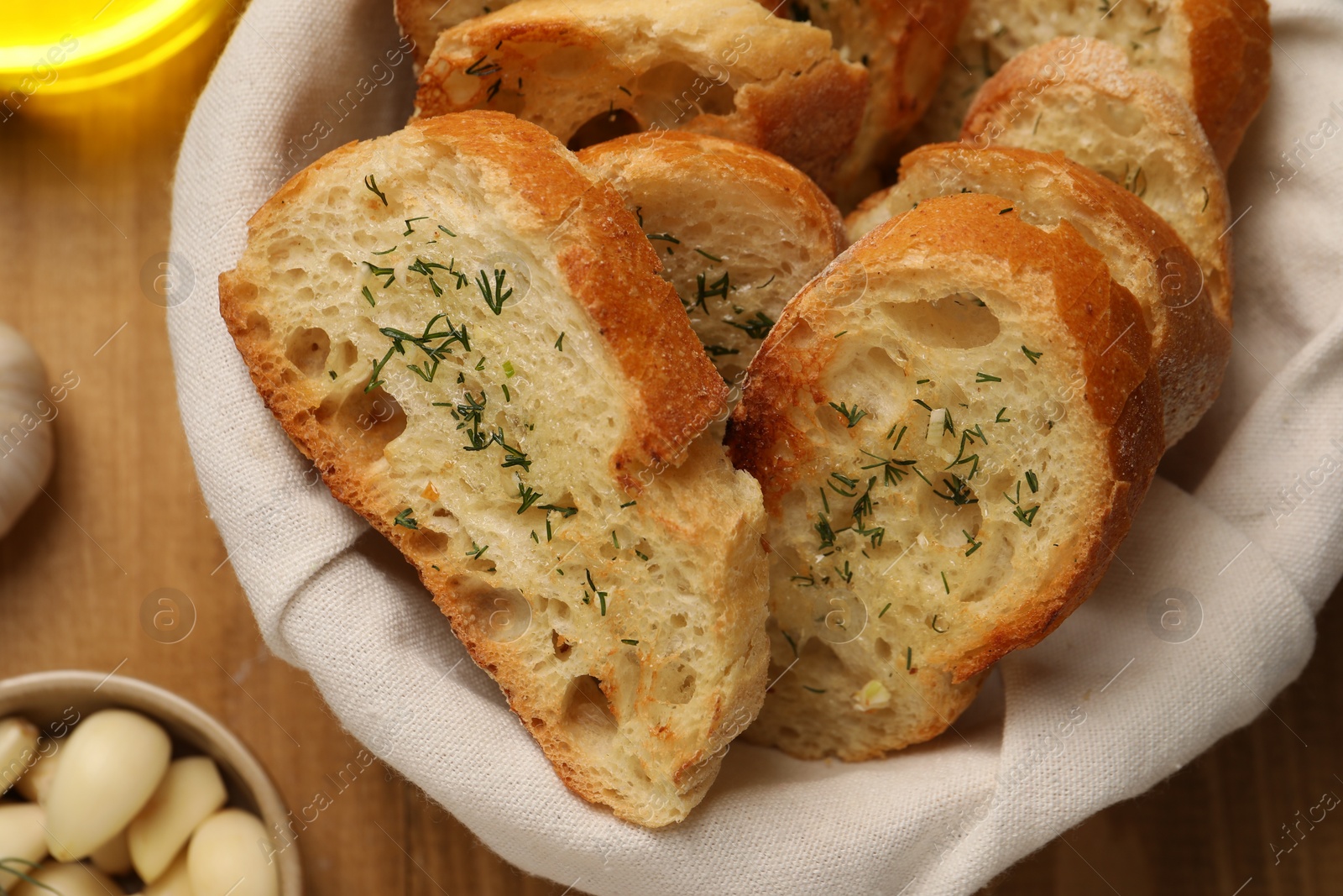 Photo of Tasty baguette with garlic and dill on wooden table, flat lay