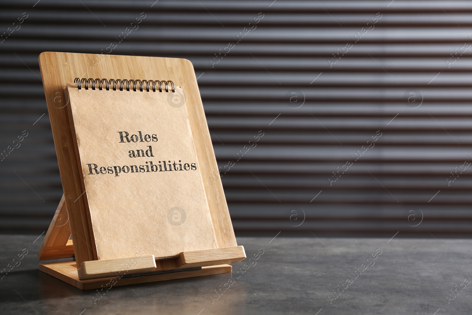 Image of Notebook with phase Roles and Responsibilities on grey stone table, space for text