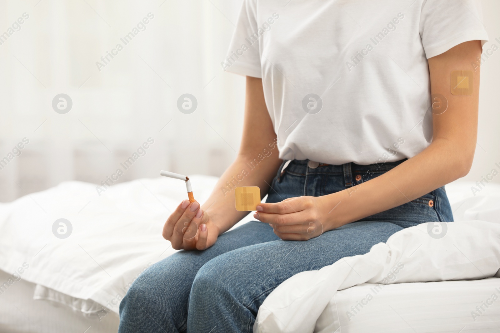 Photo of Young woman with nicotine patch and cigarette in bedroom, closeup