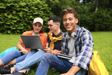 Photo of Happy young students learning together on green grass in park