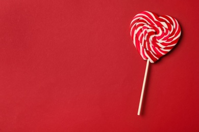 Photo of Sweet heart shaped lollipop on red background, top view with space for text. Valentine's day celebration