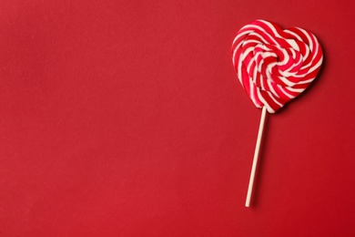 Sweet heart shaped lollipop on red background, top view with space for text. Valentine's day celebration