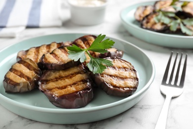 Delicious grilled eggplant slices on white marble table, closeup