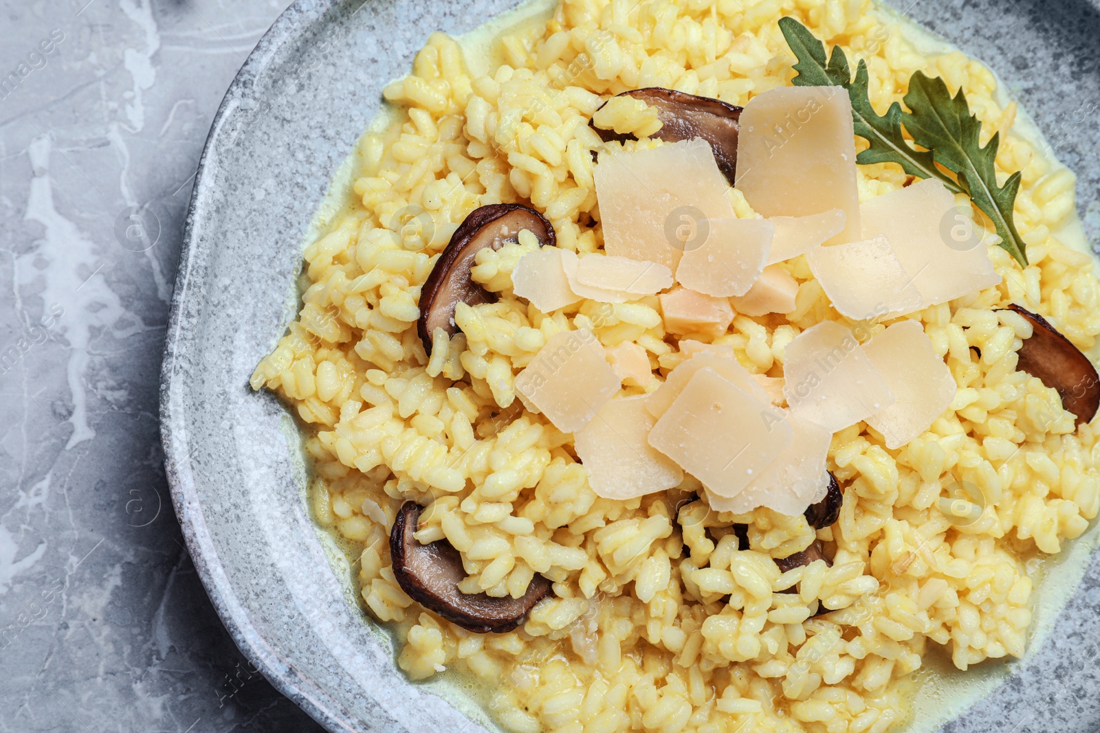 Photo of Delicious risotto with cheese and mushrooms on grey marble table, top view