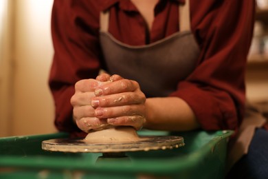 Photo of Woman crafting with clay on potter's wheel indoors, closeup