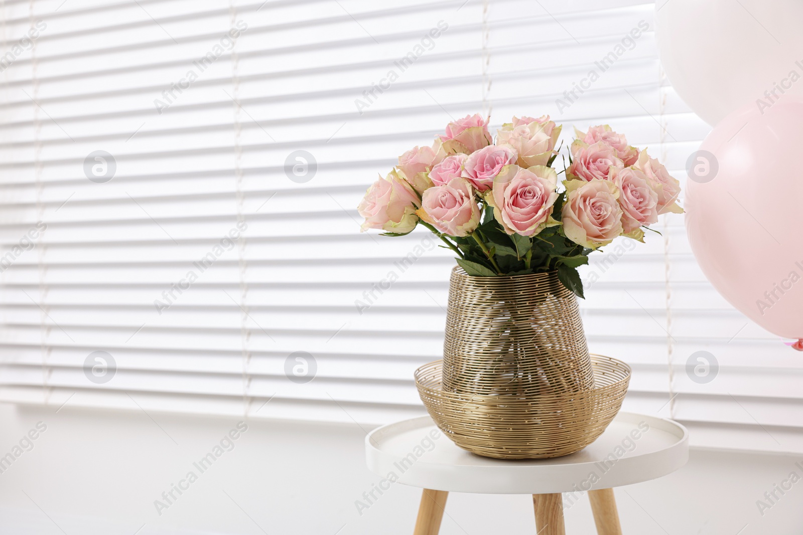 Photo of Beautiful bouquet of rose flowers on coffee table and air balloons in room, space for text. Happy birthday