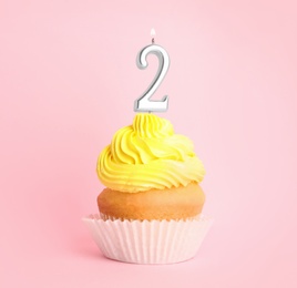 Birthday cupcake with number two candle on pink background