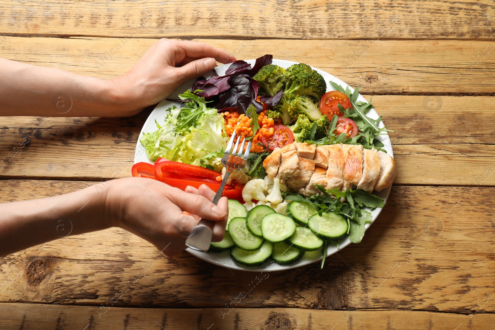 Photo of Balanced diet and healthy foods. Woman eating dinner at wooden table, closeup