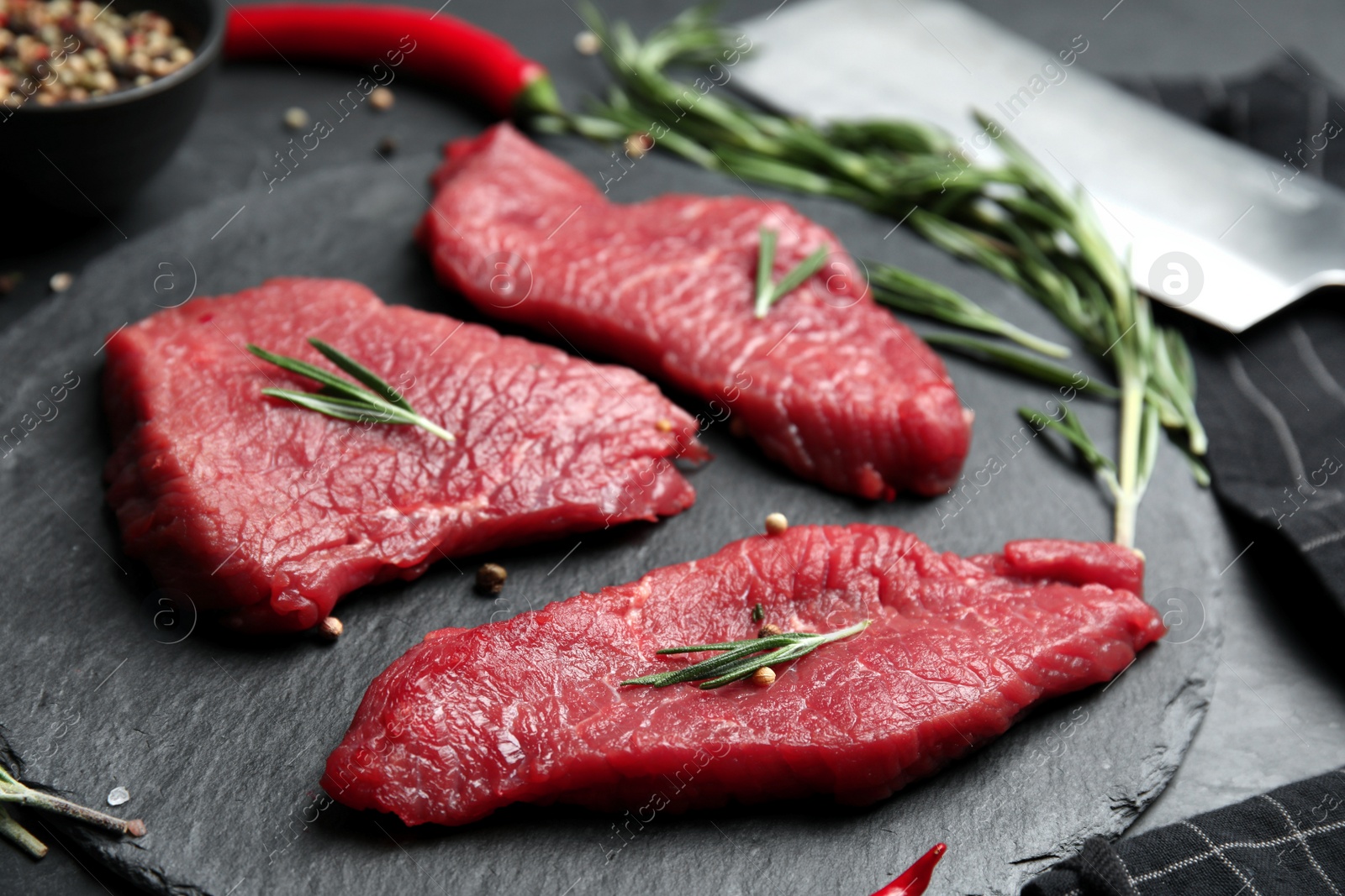 Photo of Fresh raw meat steaks and spices on black table, closeup