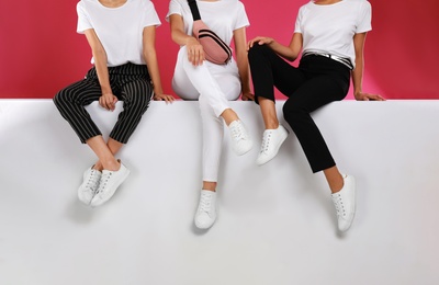 Women wearing stylish shoes on color background, closeup