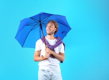 Man with blue umbrella on color background. Space for text