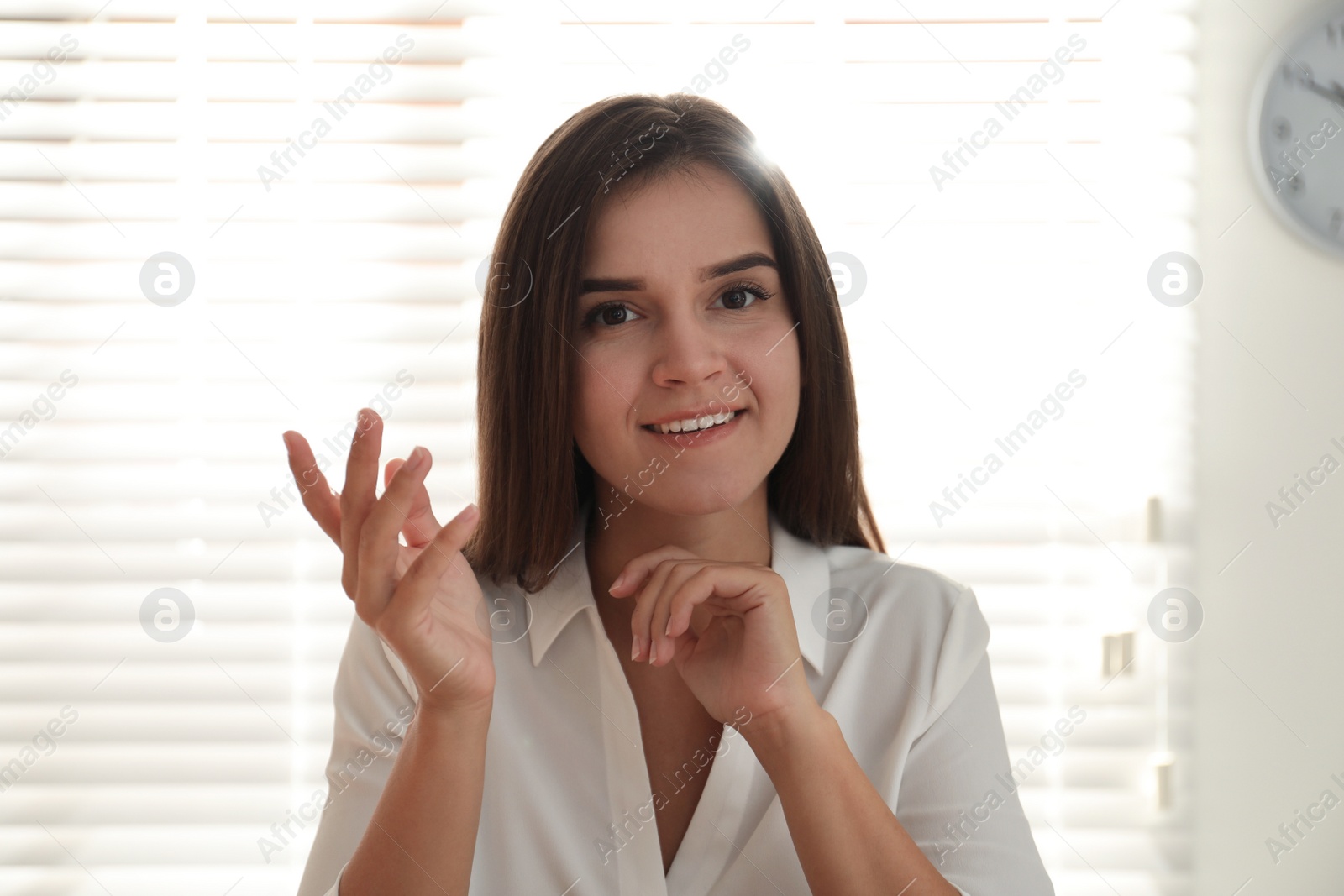 Photo of Young woman talking to her coworkers through video conference in office, view from webcam