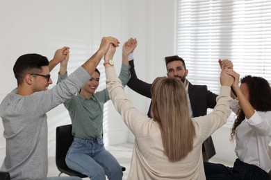 Photo of People holding hands at group therapy session indoors