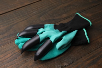 Photo of Pair of claw gardening gloves on wooden table