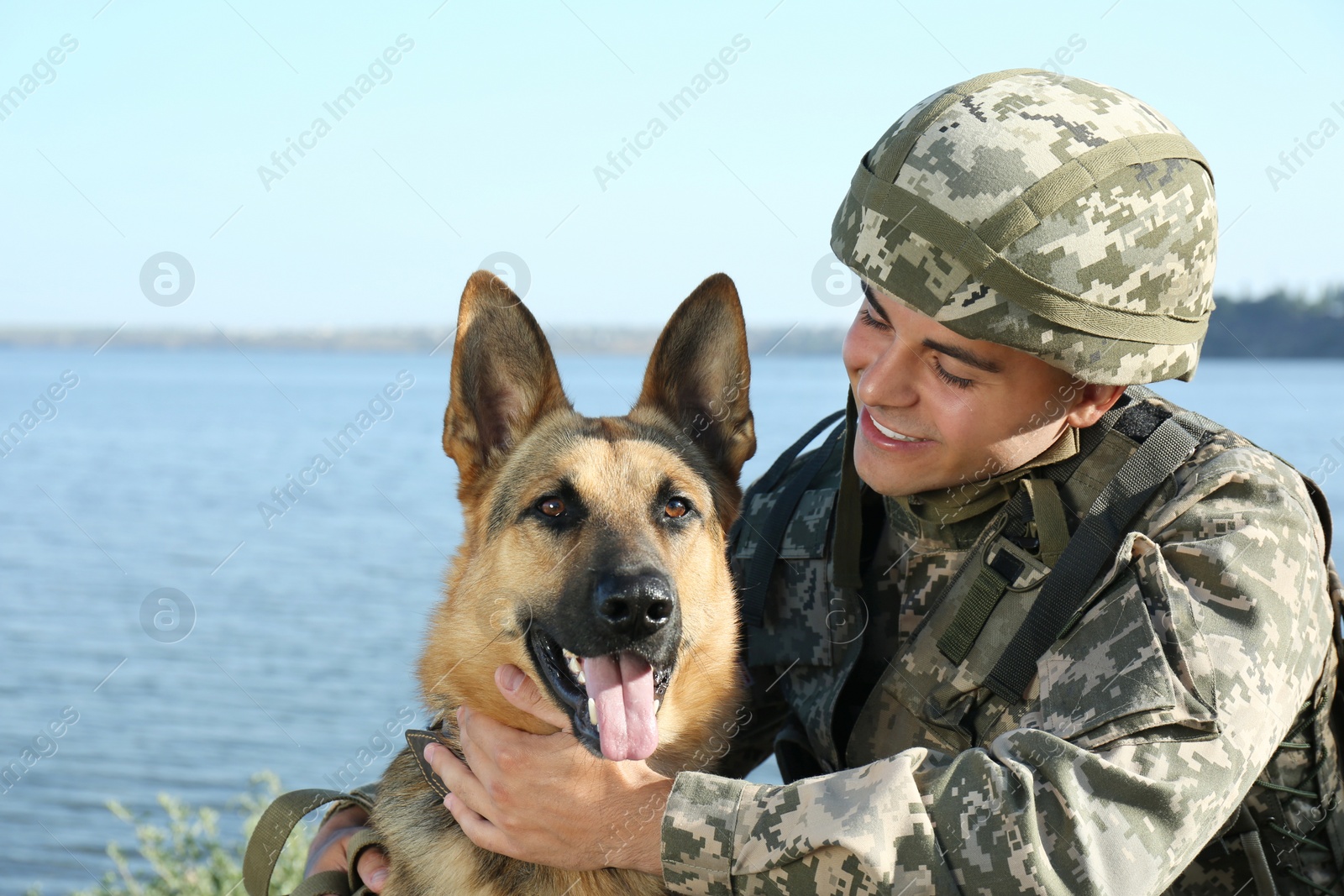 Photo of Man in military uniform with German shepherd dog near river