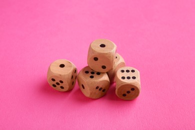 Photo of Many wooden game dices on pink background