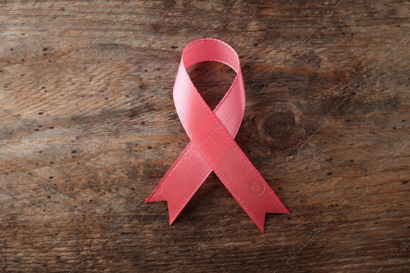 Photo of Pink ribbon on wooden background, top view. Breast cancer awareness concept