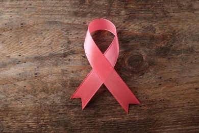 Photo of Pink ribbon on wooden background, top view. Breast cancer awareness concept